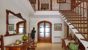 A spacious foyer with a grand staircase, a wooden reception desk, and a large mirror. - Villa "Plomera" with Private Pool & Wi-Fi (POLLENSA)