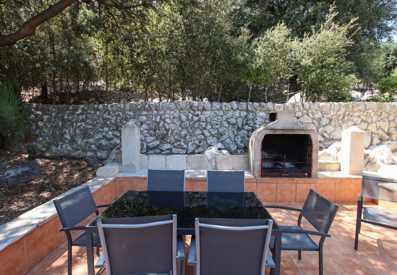 An outdoor patio with stone walls, a built-in grill, and a seating area with chairs.