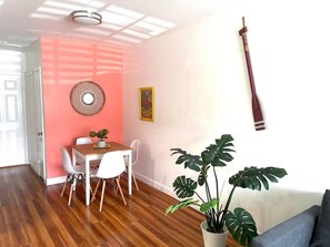 Un coin repas avec une table et des chaises en bois, une plante en pot et une guitare accrochée au mur.