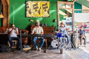 A band performing in a room with green walls, a piano, drums, and a keyboard.