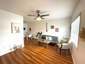 Un salon doté d’un ventilateur de plafond, d’un coin repas et d’un canapé.