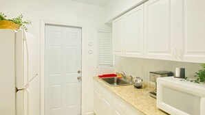 A compact kitchen with white cabinets, a stainless steel sink, and a microwave.