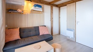 Ein modernes Zimmer mit einer Couch, einem kleinen Tisch, einem hängenden Regal mit gefalteter Kleidung und einer Tür mit einem Heizkörper.