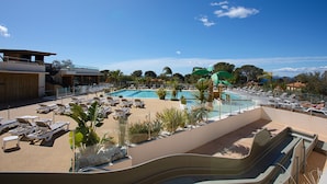 Ein Resort-Poolbereich mit Liegestühlen, einer Wasserrutsche und Blick auf die umliegende Landschaft.