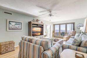 Un salon équipé d’un téléviseur, de canapés, d’un ventilateur de plafond et d’une grande fenêtre offrant une belle vue.
