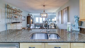 Una cocina con encimeras de granito, pileta de acero inoxidable y un comedor con candelabro.