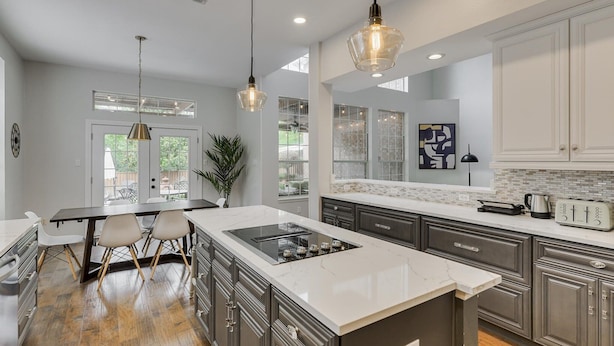 A modern kitchen with a central island, dark cabinetry, and pendant lighting.