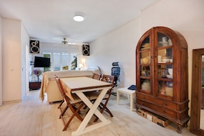 Un comedor con una mesa y sillas, un mueble de madera con puertas de cristal y un televisor fijado a la pared.