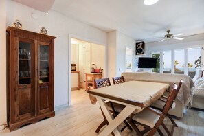 Un comedor con una mesa y sillas de madera, un armario con puertas de vidrio y un televisor montado en la pared.