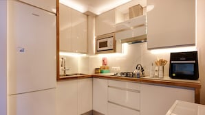 A modern kitchen with white cabinets, a microwave, a stove, and a refrigerator. - Apartment “Chipiona, Cruz del Mar 1st Line” with Sea Views, Terrace, Parking & Wi-Fi (Chipiona)