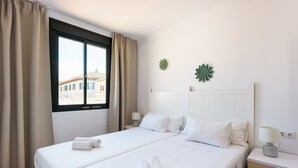 Habitación de hotel con dos camas, una ventana con cortinas, una mesita de noche con lámpara y un adorno en la pared.