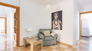 Una sala de estar moderna con un sofá gris, una mesita de madera, una lámpara y una obra de arte grande con marco en la pared.