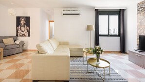 Una sala de estar moderna con un sofá, una mesa de centro, aire acondicionado, una lámpara y una ventana con vistas.