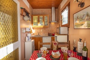 A compact kitchen with a dining table set for two, a small refrigerator, and a microwave.