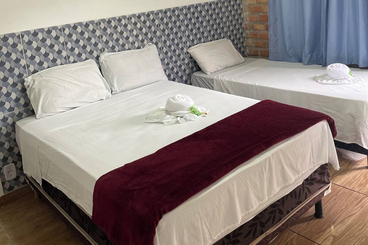 A hotel room with two beds, a brick wall, and a blue curtain.