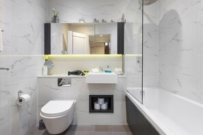 Een moderne badkamer met toilet, wastafel en bad.