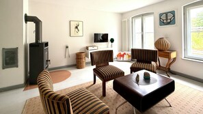 Een woonkamer met gestreepte meubels, een open haard, een televisie en een raam met uitzicht.