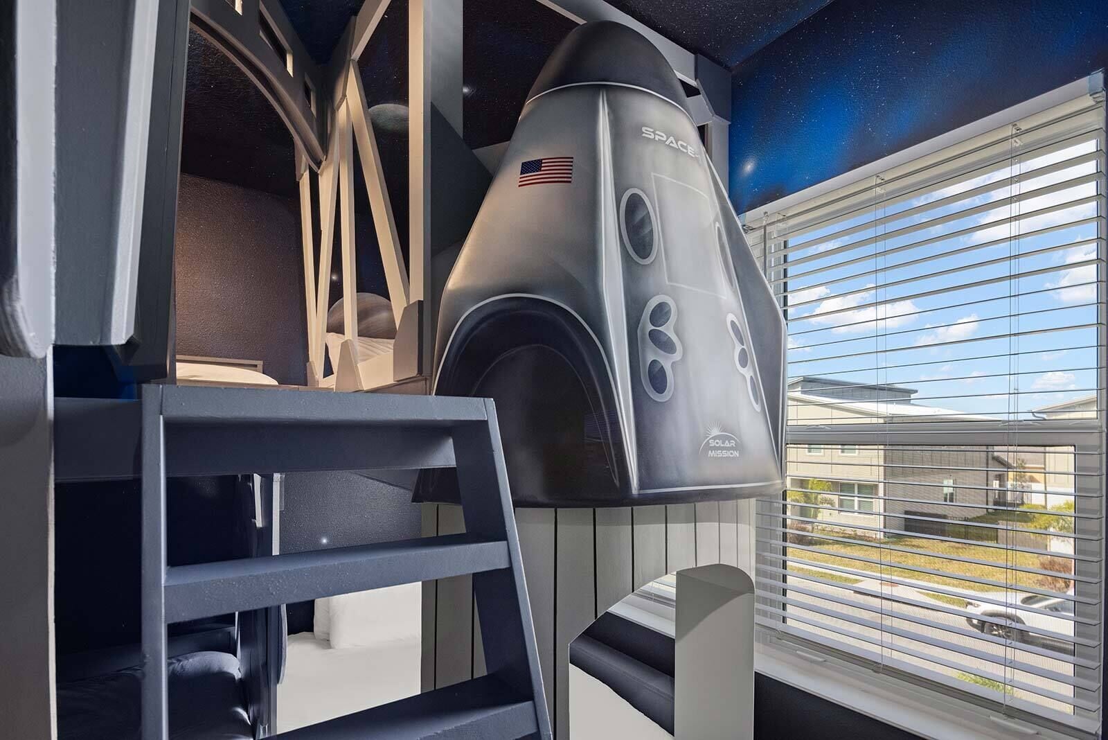 A room with a bunk bed, a space-themed wall, and a window with blinds.