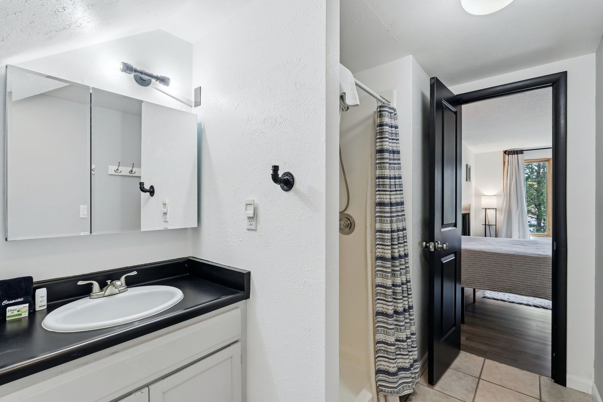 A bathroom with a sink, mirror, and shower curtain.