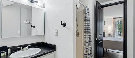 A bathroom with a sink, mirror, and shower curtain.