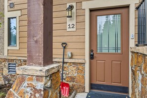 Une maison avec des fondations en pierre, une porte marron et une plaque portant le numéro « 12 ».
