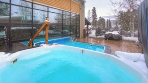 A hot tub area with a wooden deck and a glass wall. - Claimjumper Condo - Hot Tub, Pool, Bus Route, Free Parking (Breckenridge)