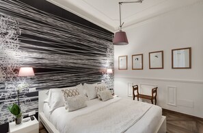 Une chambre à coucher moderne avec un grand lit, une table de chevet avec une lampe et un fauteuil.