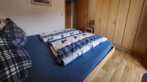 Ett sovrum med en säng, en garderob, en stol och en tavla på väggen.