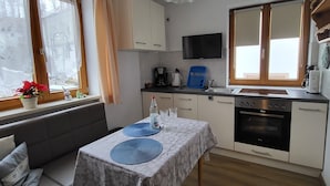 Ett kompakt kök med en matplats, en soffa och en TV som är monterad på väggen.