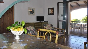 Uma área de refeições com mesa, cadeiras e uma tigela de frutas.