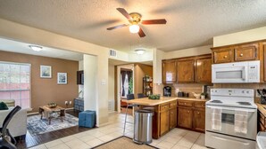 A modern kitchen with wooden cabinets, a microwave, and a stove. There is a dining area with a table and chairs. - Entire Apt | Gated Parking | KING Bed | Computer (Houston)
