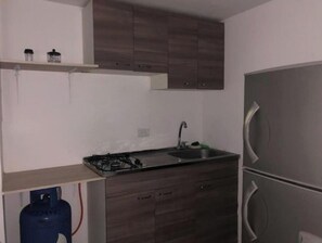A compact kitchen with a gas stove, sink, and a stainless steel refrigerator. - Comfortable, central and well located - Apt 202 (Medellín)