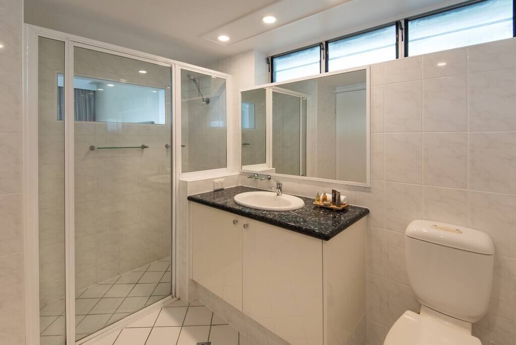 A modern bathroom with a glass-enclosed shower, a white sink, and a large mirror.