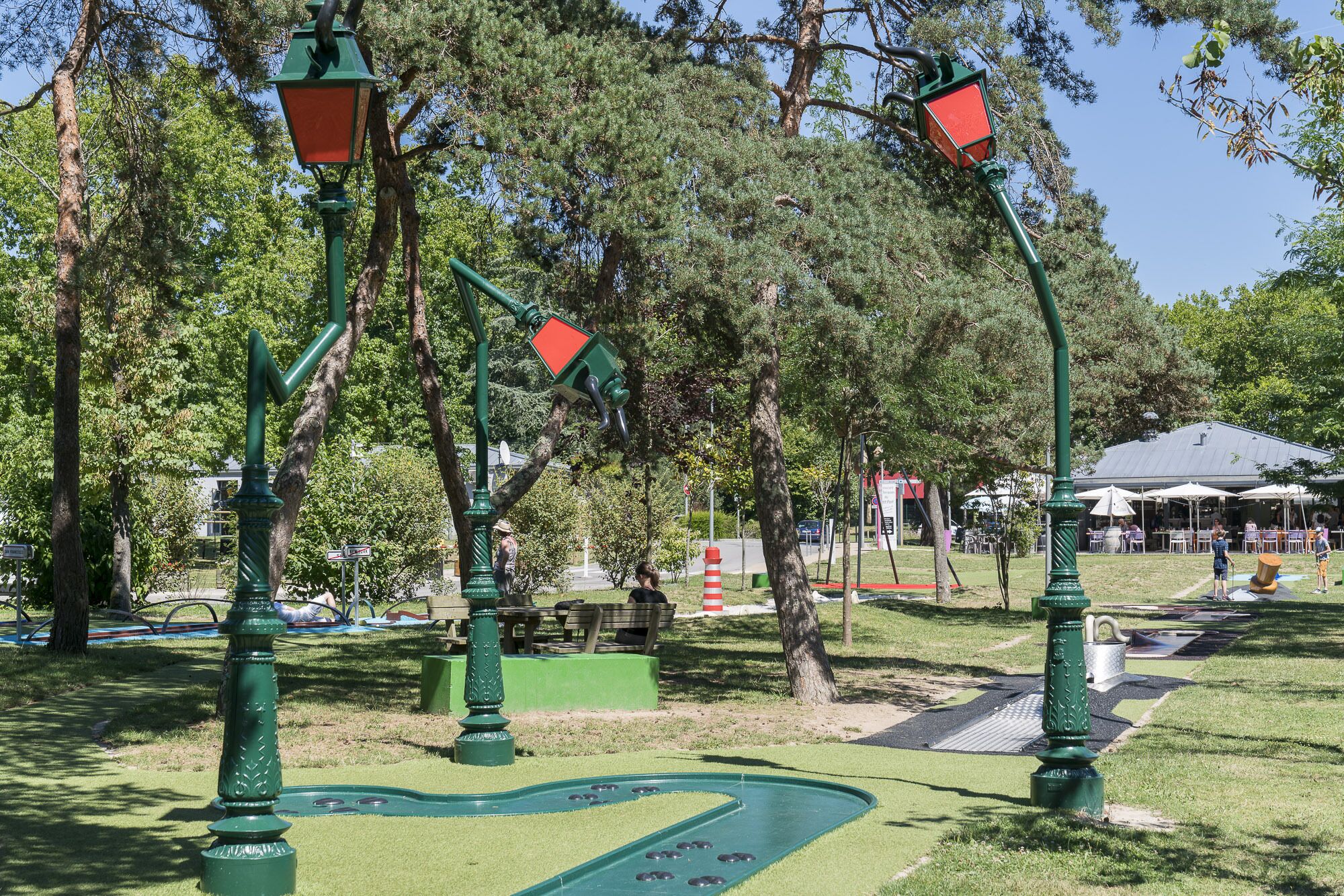 Ein Park mit grünen Lampen, einem grünen Shuffleboard-Tisch und Picknicktischen.