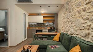 A modern kitchen with a stone accent wall, a dining area with a green sofa, and a wooden table with kitchenware.
