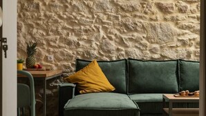 A cozy room with a green sofa, a yellow pillow, and a rustic stone wall.