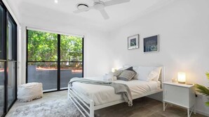 Ein Schlafzimmer mit Bett, Nachttisch und Deckenventilator.