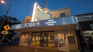 A cinema with a marquee reading 'TOWER' and a tall building in the background.