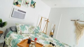 A bedroom with a bed, a bedside table with a tray, a hanging macrame wall decoration, and a ceiling light fixture.