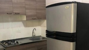 A kitchen with a stainless steel refrigerator, a gas stove, and wooden cabinets. - Comfortable, central and well located apartment - Apt 201 (Medellín)