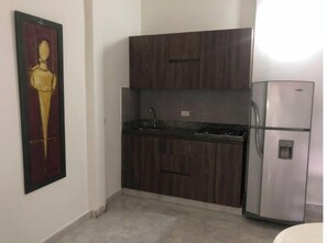 A kitchen with dark wooden cabinets, a stainless steel refrigerator, and a sink. - Comfortable, central and well located apartment - Apto 404 (Medellín)
