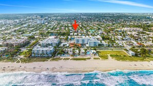 An aerial view of a coastal city with a beach, residential areas, and a prominent hotel with multiple floors and a swimming pool. - 3 Queen Beds, 5 min Walk to the Beach - 70 inch Smart TV (Lauderdale-by-the-Sea)