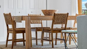 A dining table with a woven bowl centerpiece, surrounded by four wicker chairs with woven seats. - 3 Queen Beds, 5 min Walk to the Beach - 70 inch Smart TV (Lauderdale-by-the-Sea)