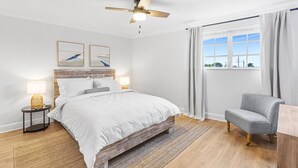 A bedroom with a bed, a chair, a ceiling fan, a window with curtains, and artwork on the wall. - 3 Queen Beds, 5 min Walk to the Beach - 70 inch Smart TV (Lauderdale-by-the-Sea)