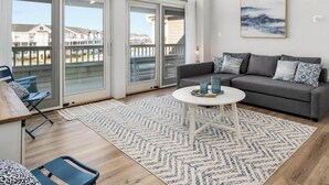 Una sala de estar moderna con un sofá gris, una mesa de centro redonda y una alfombra estampada.