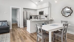 Una cocina moderna con armarios blancos, electrodomésticos de acero inoxidable y una isla central.