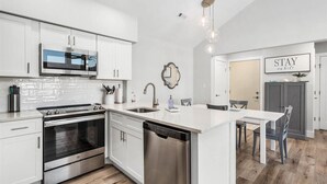 Cocina moderna con armarios blancos, electrodomésticos de acero inoxidable y una isla central.