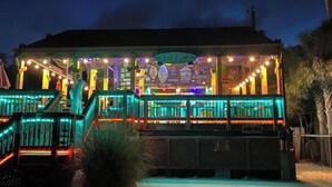 Un edificio bien iluminado con un espacio exterior techado, escalones que lo conducen y un cartel.