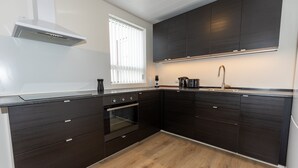 A modern kitchen with dark cabinetry, a built-in oven, and a window with blinds.