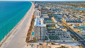 Un paisaje urbano costero con un hotel frente a la playa, una amplia zona de estacionamiento y una combinación de edificios residenciales y comerciales.